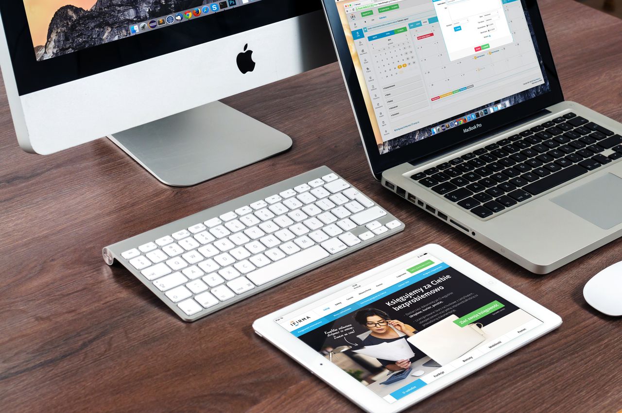 Un aménagement de bureau raffiné mettant en avant des appareils Apple : iMac, MacBook et iPad.